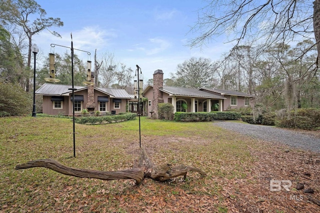 view of front facade featuring metal roof, a chimney, and a front yard