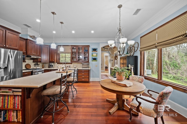 kitchen with wood finished floors, visible vents, ornamental molding, stainless steel appliances, and under cabinet range hood