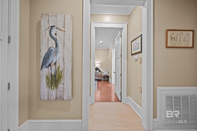 hall featuring light tile patterned floors, visible vents, baseboards, and crown molding