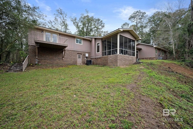 back of property featuring a yard, central air condition unit, brick siding, and a sunroom