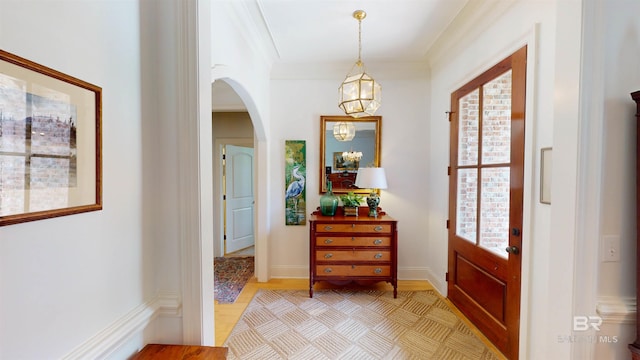 entryway with crown molding and an inviting chandelier