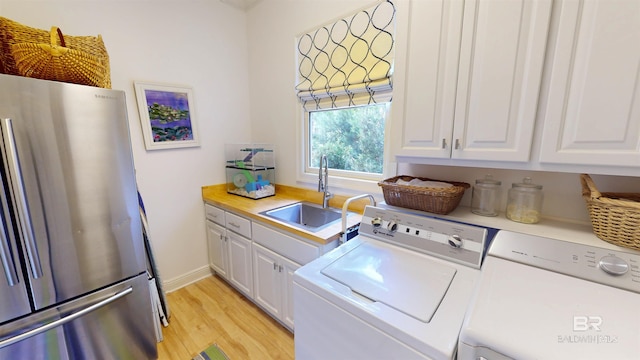 washroom with cabinets, light hardwood / wood-style floors, sink, and separate washer and dryer