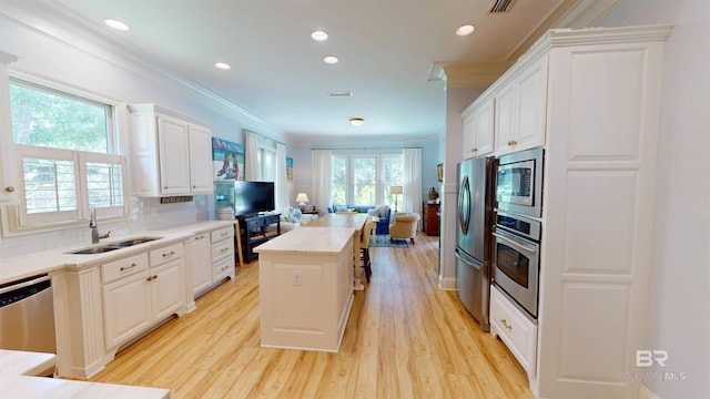 kitchen with white cabinets, appliances with stainless steel finishes, a healthy amount of sunlight, and a kitchen island