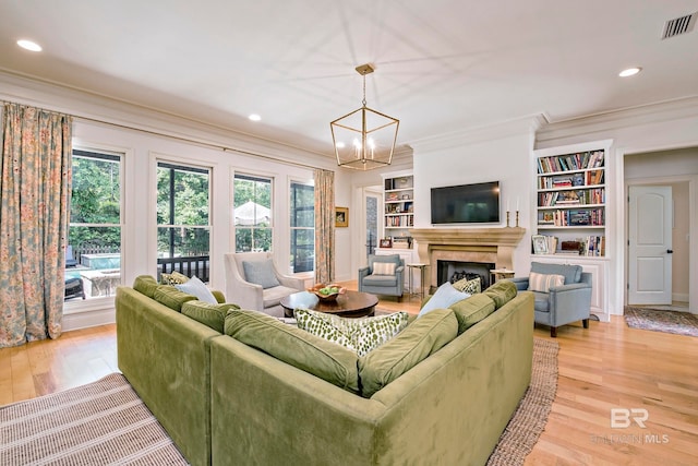 living room featuring built in features, an inviting chandelier, light hardwood / wood-style floors, and crown molding