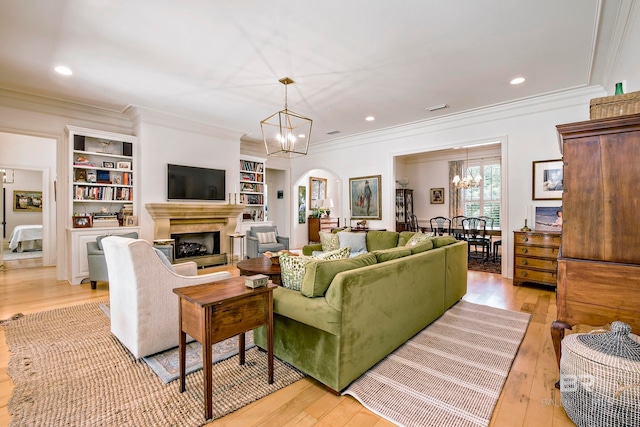 living room with built in features, crown molding, and light hardwood / wood-style flooring