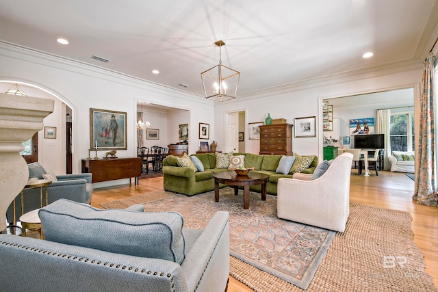 living room with a chandelier, light wood-type flooring, and ornamental molding