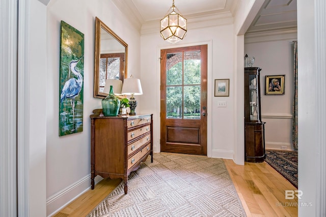 foyer entrance with light hardwood / wood-style flooring, crown molding, and a notable chandelier