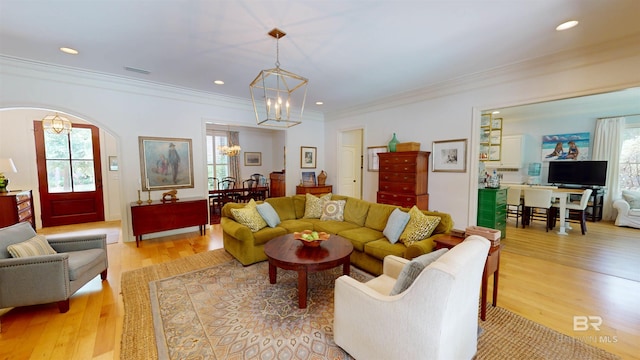 living room with light wood-type flooring, an inviting chandelier, and crown molding