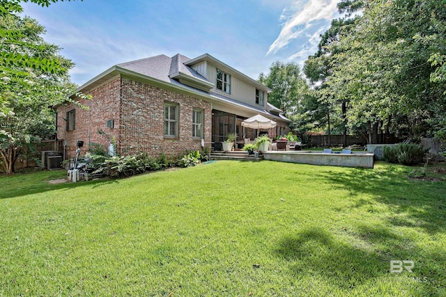 rear view of property featuring cooling unit and a yard