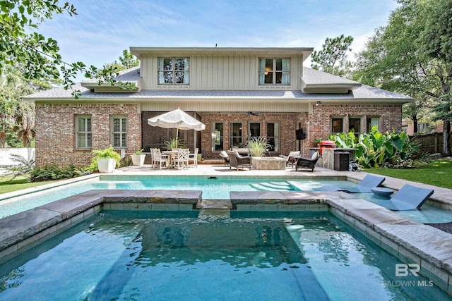 back of property with an outdoor hangout area, a swimming pool with hot tub, and a patio area