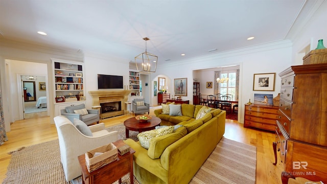 living room featuring light hardwood / wood-style flooring, a chandelier, crown molding, and built in features