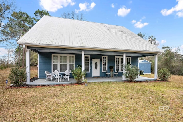 view of front facade with covered porch, metal roof, and a front lawn