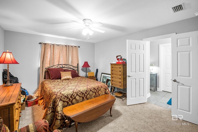 bedroom featuring light tile patterned flooring, ceiling fan, visible vents, and light colored carpet