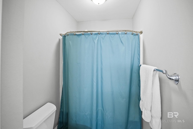 full bath with toilet and a shower with shower curtain