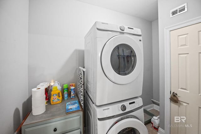 washroom with laundry area, baseboards, visible vents, and stacked washer / drying machine