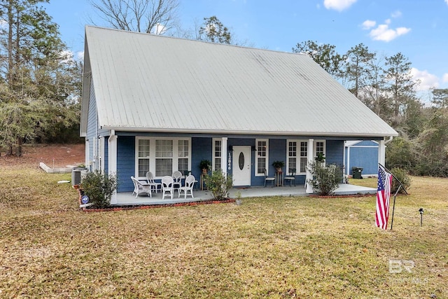 view of front of property with metal roof, a front lawn, cooling unit, and covered porch