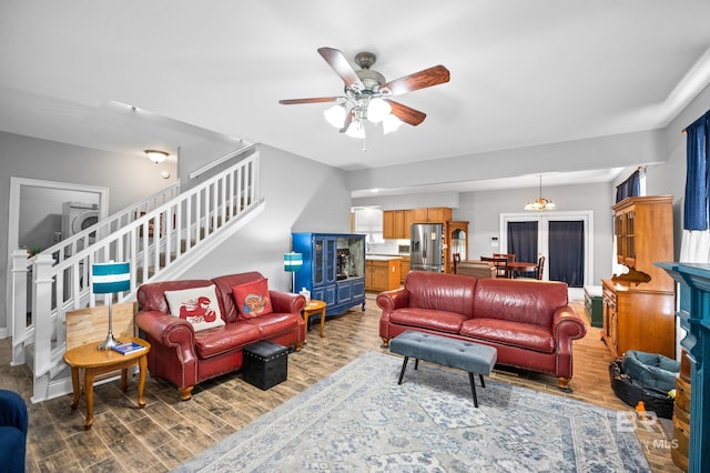 living area with washer / dryer, wood finished floors, ceiling fan, and stairs