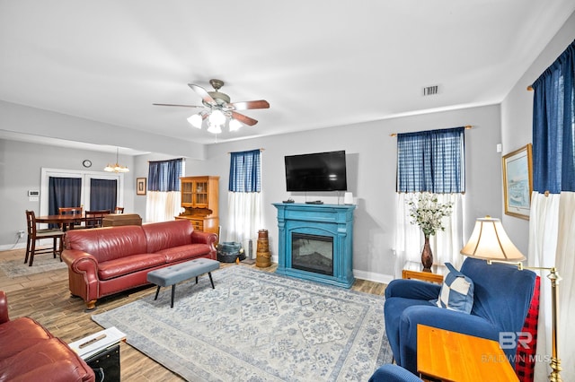 living area with baseboards, visible vents, wood finished floors, and a glass covered fireplace