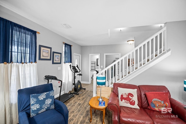 living area featuring wood finished floors, visible vents, a healthy amount of sunlight, stairs, and baseboards