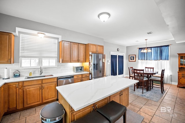 kitchen featuring pendant lighting, visible vents, decorative backsplash, appliances with stainless steel finishes, and a sink