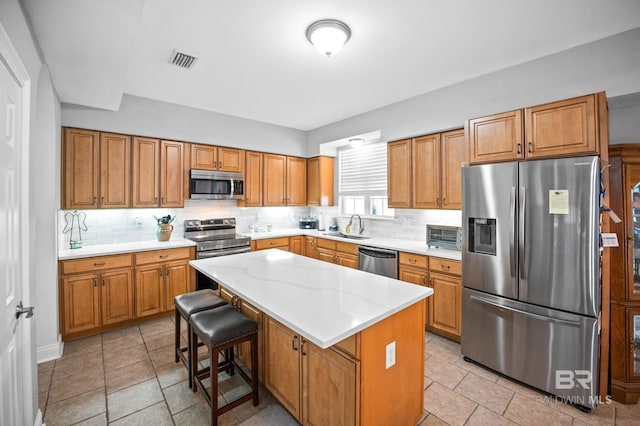 kitchen with tasteful backsplash, visible vents, a center island, stainless steel appliances, and a sink