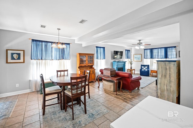 tiled dining area featuring baseboards, visible vents, and ceiling fan with notable chandelier