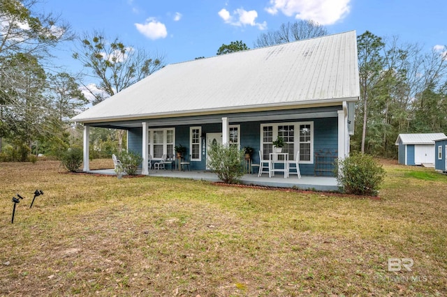 exterior space with a front yard, covered porch, metal roof, and an outbuilding