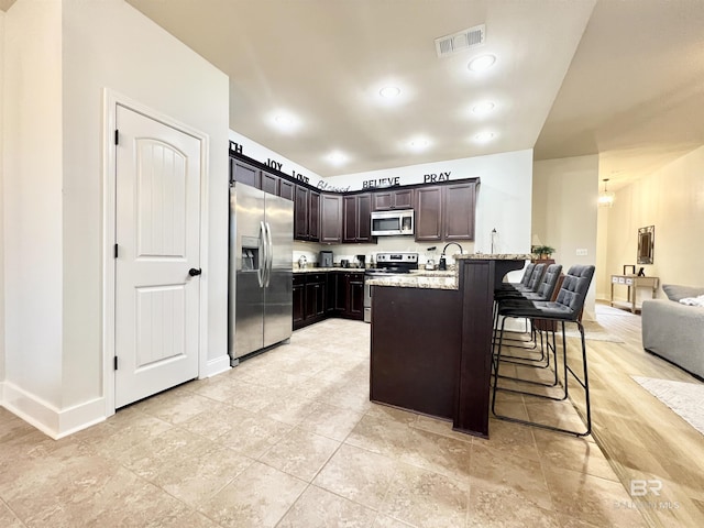14775 Sonoma Blvd, Silverhill, AL 36576 - kitchen featuring visible vents, dark brown cabinets, a peninsula, a kitchen breakfast bar, and stainless steel appliances
