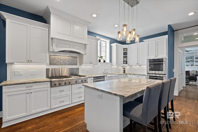 kitchen featuring a kitchen island, white cabinetry, stainless steel appliances, backsplash, and dark hardwood / wood-style floors