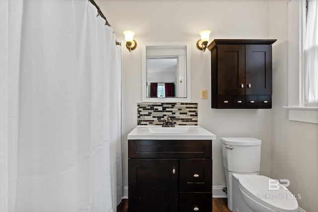 bathroom with toilet, vanity, and tasteful backsplash