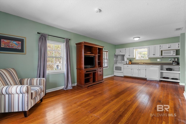 kitchen with white cabinets, white appliances, dark hardwood / wood-style floors, and a textured ceiling