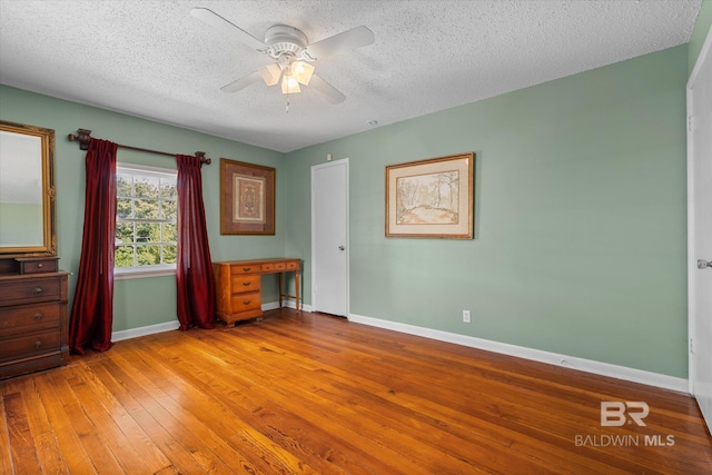 unfurnished bedroom featuring ceiling fan, light hardwood / wood-style floors, and a textured ceiling