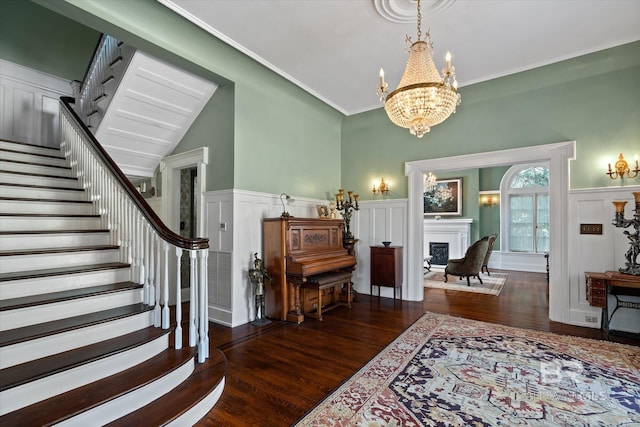 entrance foyer with dark hardwood / wood-style floors, ornamental molding, and an inviting chandelier