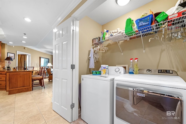 washroom with washing machine and dryer, light tile patterned flooring, and crown molding