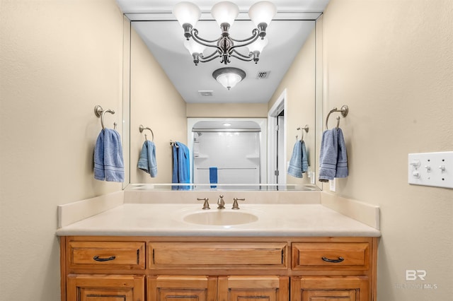 bathroom with vanity, a chandelier, and a shower