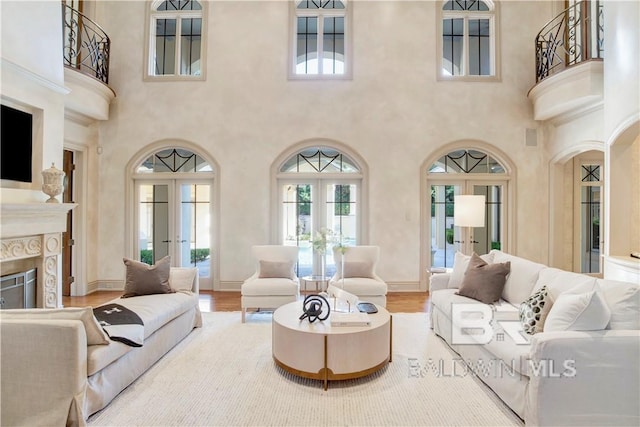 living room featuring a premium fireplace, wood-type flooring, a high ceiling, and french doors