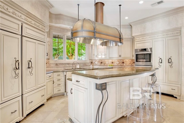 kitchen with a breakfast bar, a center island, sink, decorative light fixtures, and cream cabinets