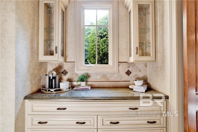 bar with cream cabinets and decorative backsplash