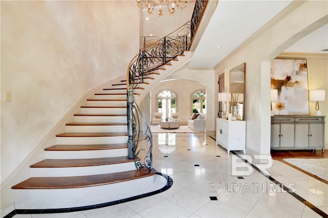 entryway featuring crown molding, a towering ceiling, light tile patterned floors, and a chandelier