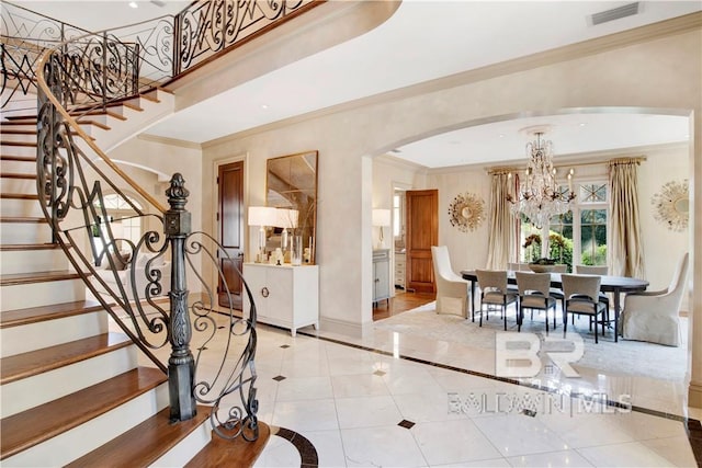 entrance foyer with light tile patterned flooring, ornamental molding, and a chandelier