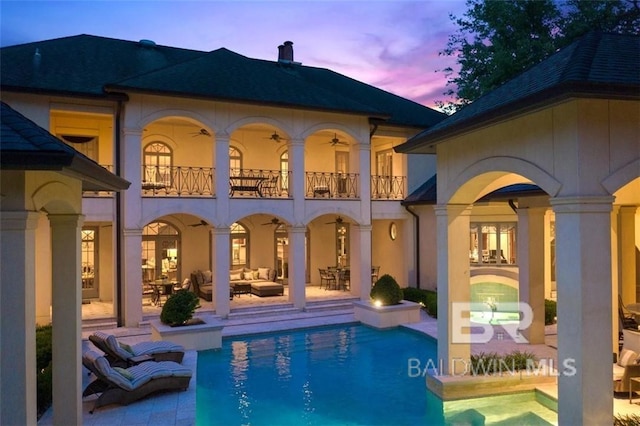 back house at dusk featuring a patio and a balcony