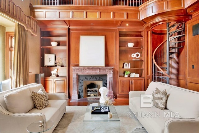 living room with built in shelves, hardwood / wood-style flooring, and a fireplace