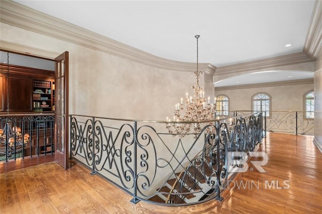 hall featuring a notable chandelier, light wood-type flooring, and crown molding