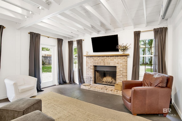 living room with beamed ceiling, a wealth of natural light, and a brick fireplace