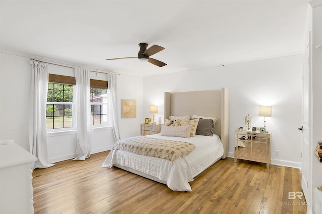 bedroom with ceiling fan, wood finished floors, and baseboards