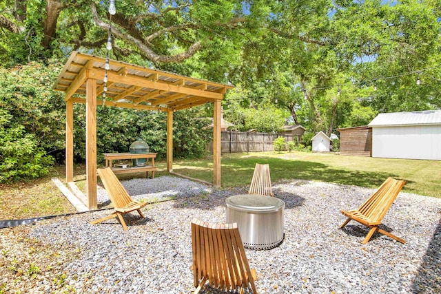 exterior space with grilling area, a fire pit, fence, an outbuilding, and a pergola