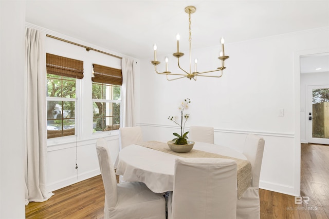 dining area featuring ornamental molding, an inviting chandelier, wood finished floors, and baseboards