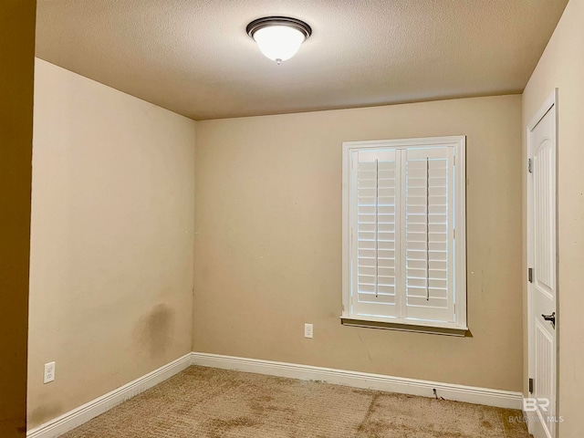 carpeted empty room featuring a textured ceiling