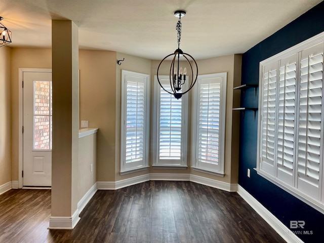 unfurnished dining area with a chandelier, baseboards, and wood finished floors