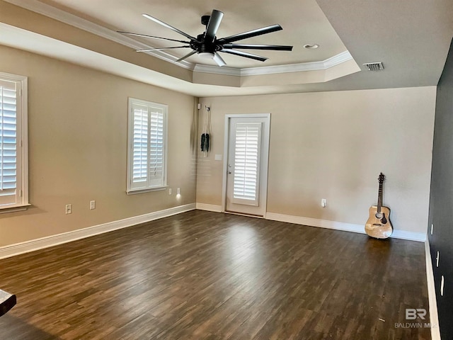 spare room featuring ceiling fan, dark hardwood / wood-style floors, a raised ceiling, and crown molding